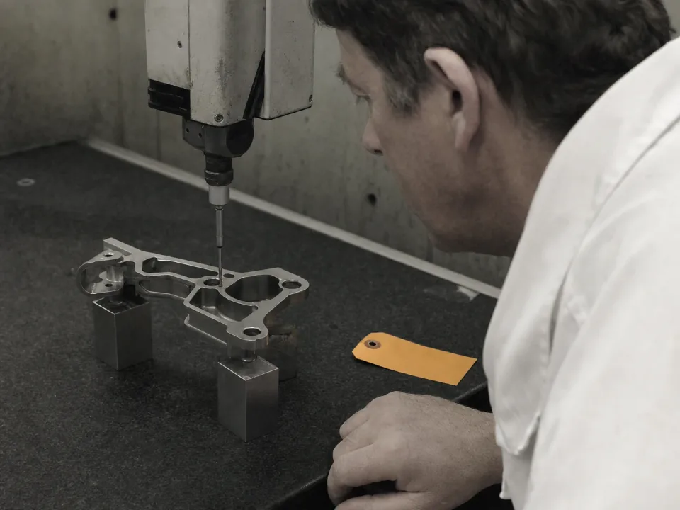 Inspector measuring an aerospace bracket on a coordinate measuring machine