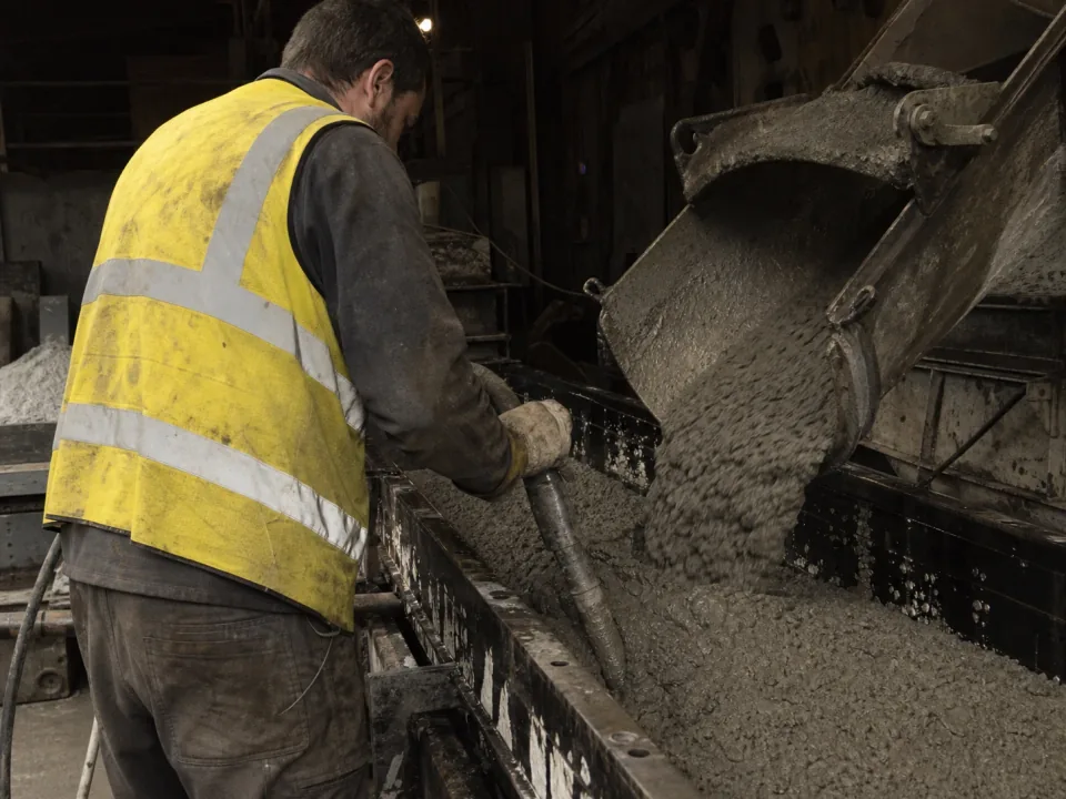 Concrete being poured into a precast mould on a factory floor
