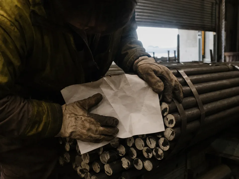 Operator checking stamped heat numbers on bundled bar stock at goods-in