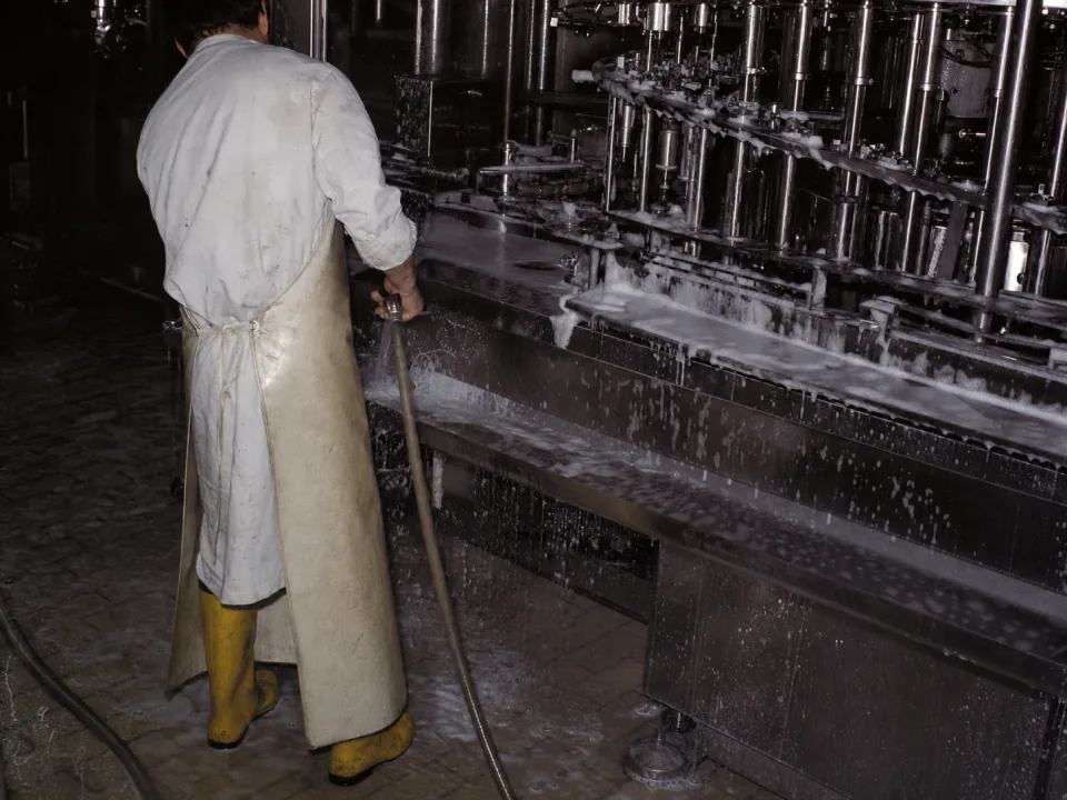 Operator washing down a stainless filling line between products