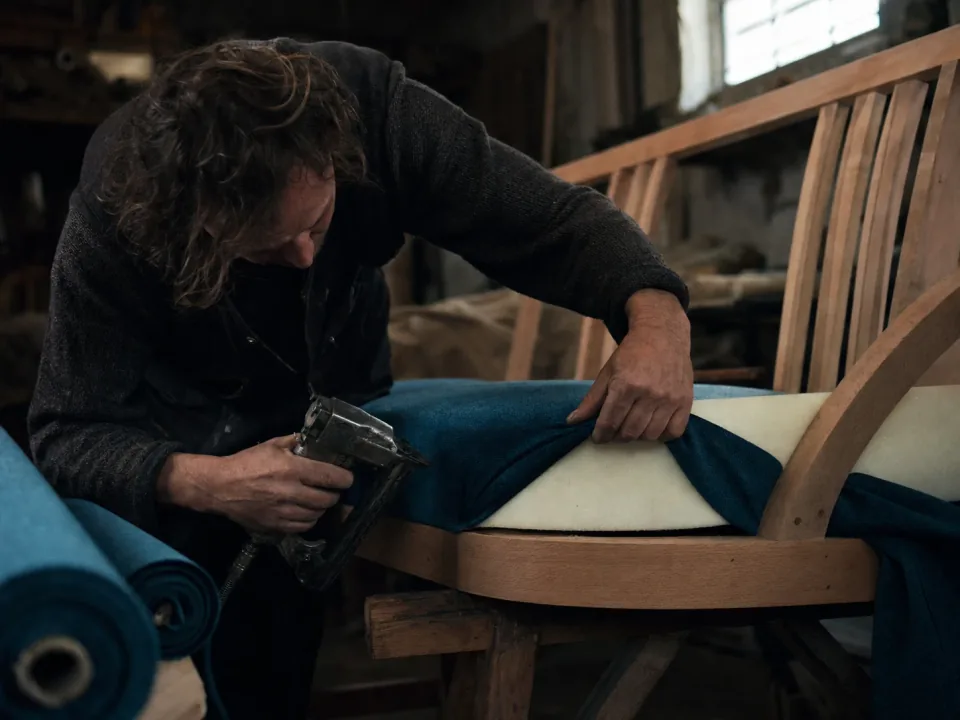 Upholsterer stapling fabric to a settee frame