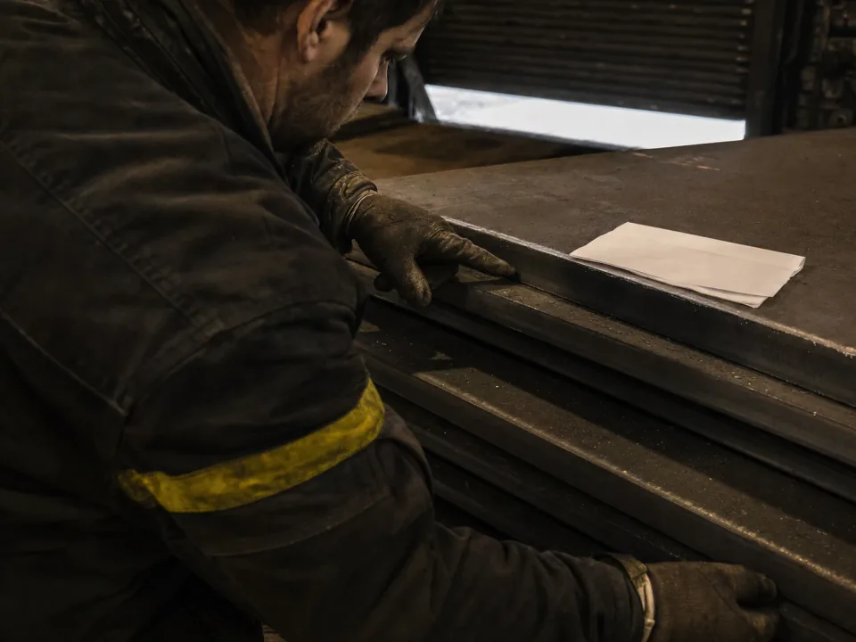 Fabricator checking a steel plate against a mill cert at the goods-in rack