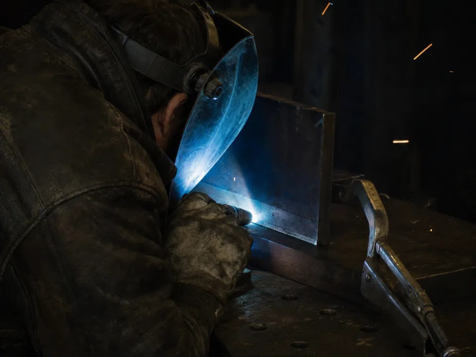 Welder working a fillet joint on a steel fabrication in a weld bay